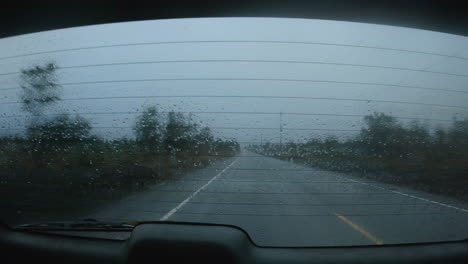 wet and foggy road races by from the rear view window of a moving vehicle