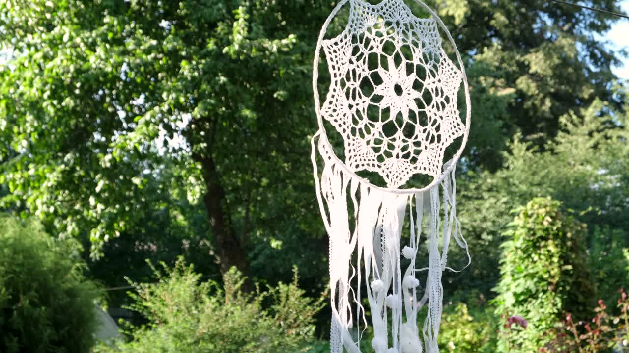 드림캐처는 여름의 자연을 배경으로 바람에 흔들립니다.