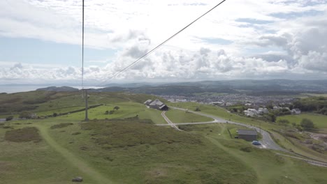 Overlooking-scenic-mountain-valley-hillside-as-colourful-cable-car-gondola-tourism-sightseeing-transportation-passes