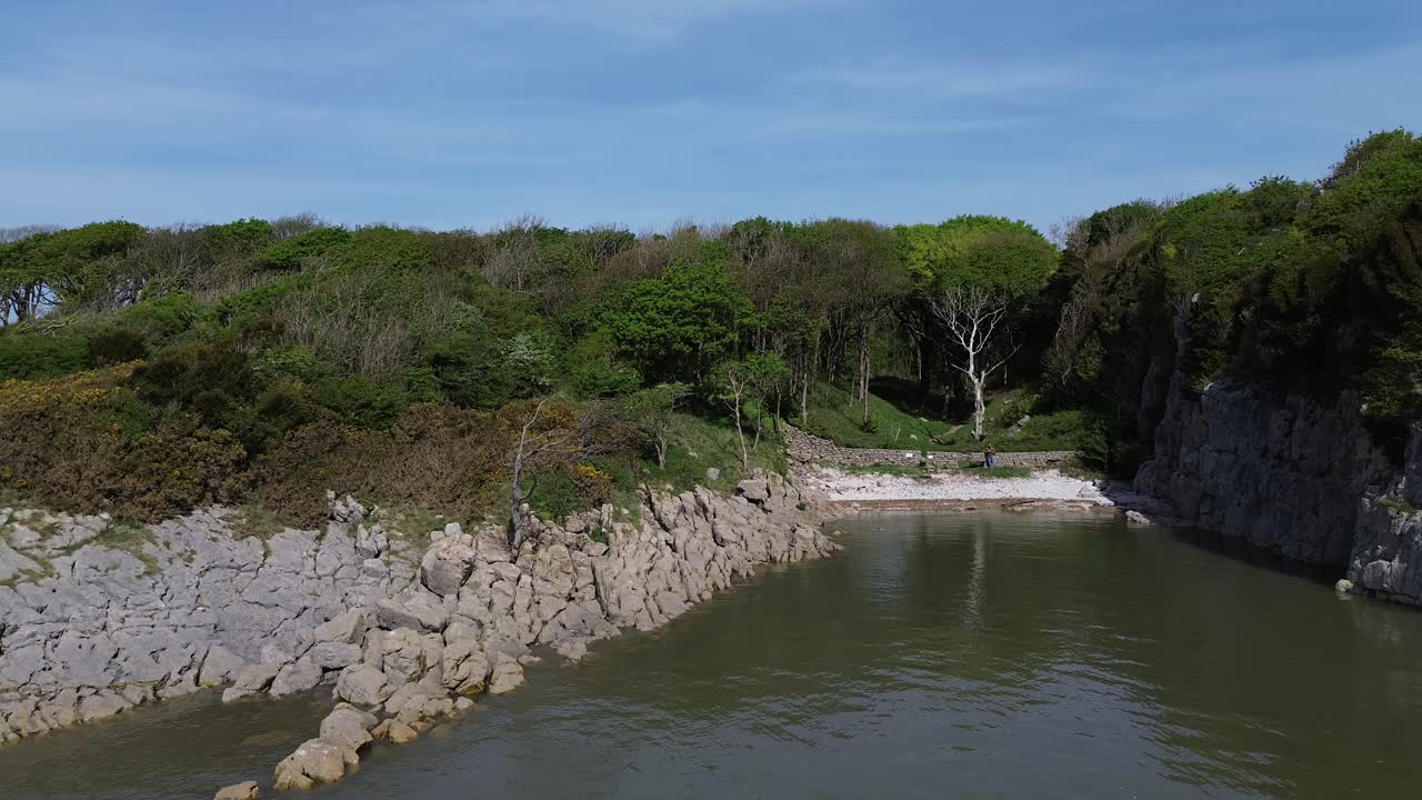 Aerial view rising above secluded lake district private rocky lush woodland beach coastline