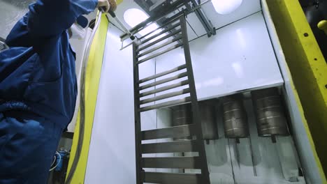 a worker paints a stainless steel metal structure with an airbrush spray gun. dry painting method.