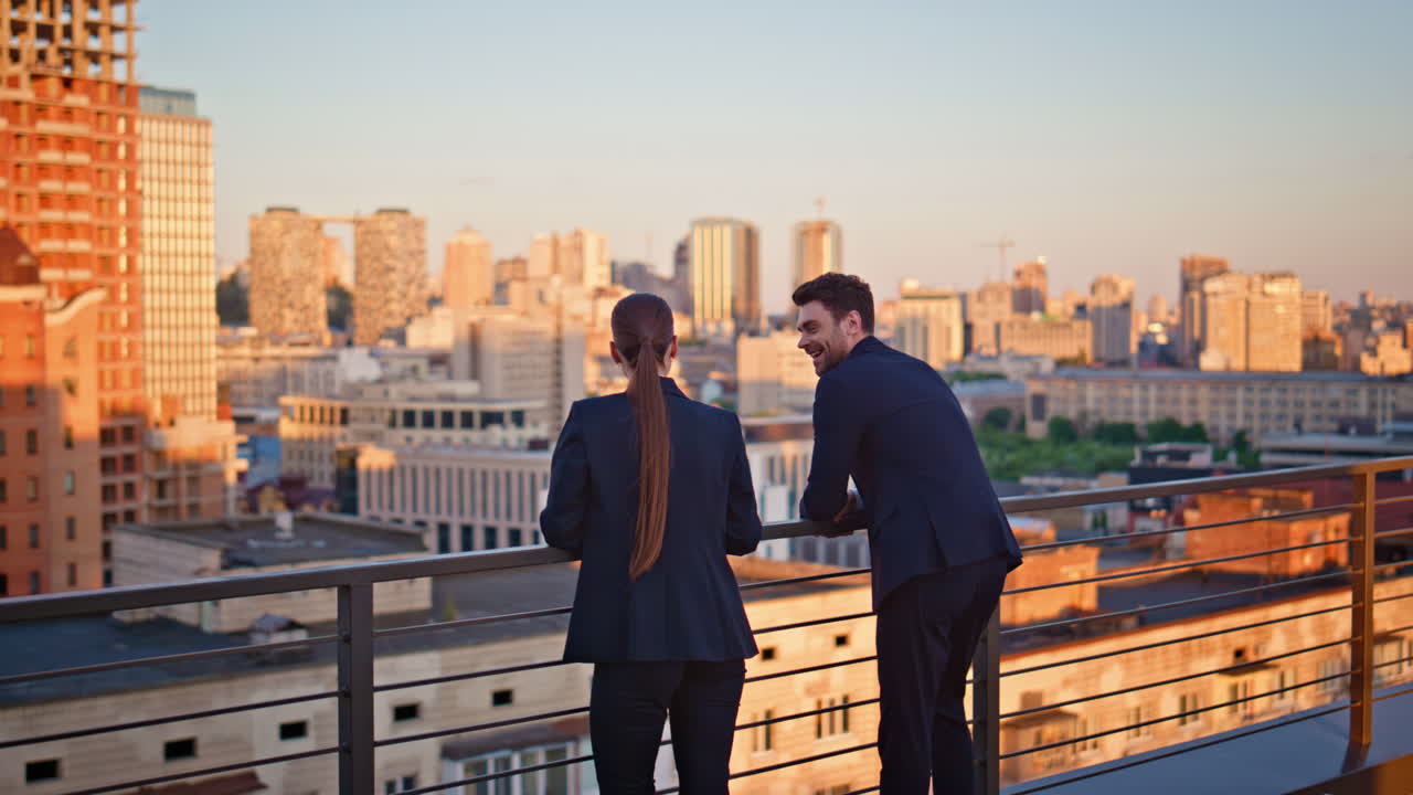 Business people standing terrace looking at cityscape in golden sunset sunlight