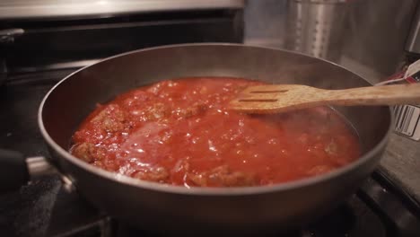 disparo a cámara lenta alrededor de una sartén de salsa de espagueti roja burbujeante en una estufa de cocina caliente
