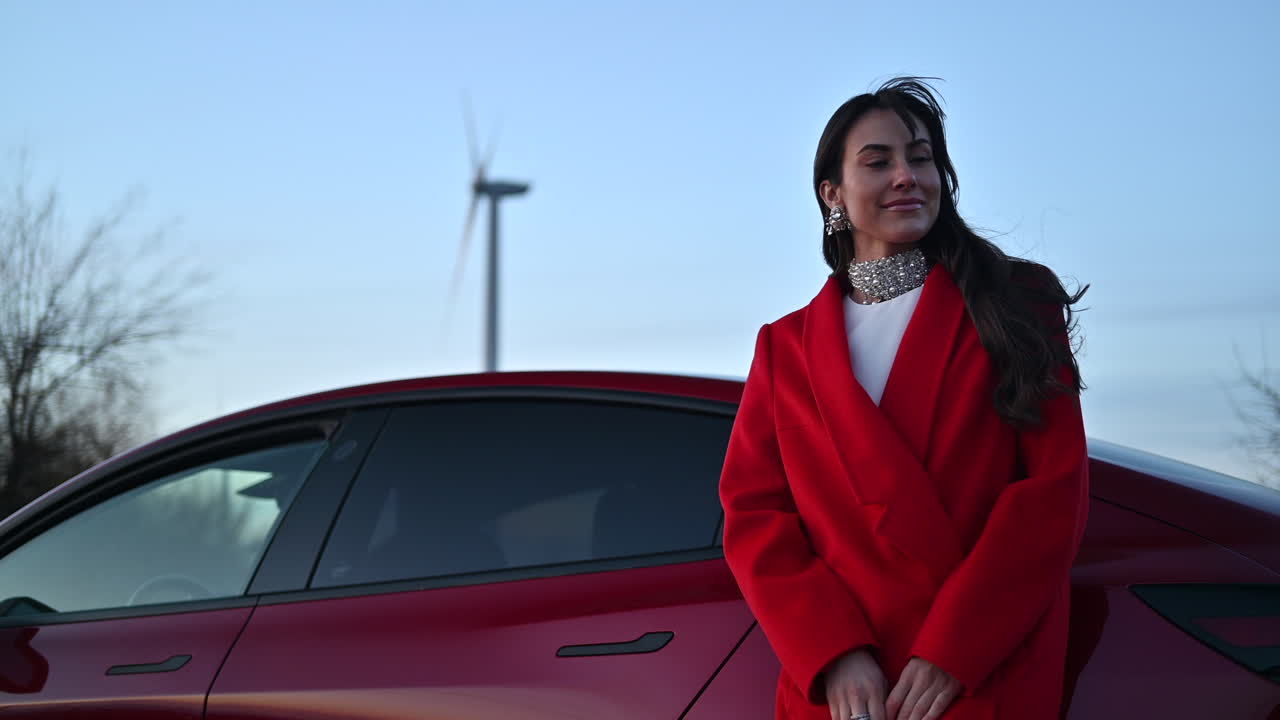 Brunette woman in red coat taking pictures in front of a red car