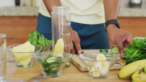 fit african american man cooking, preparing healthy green smoothie