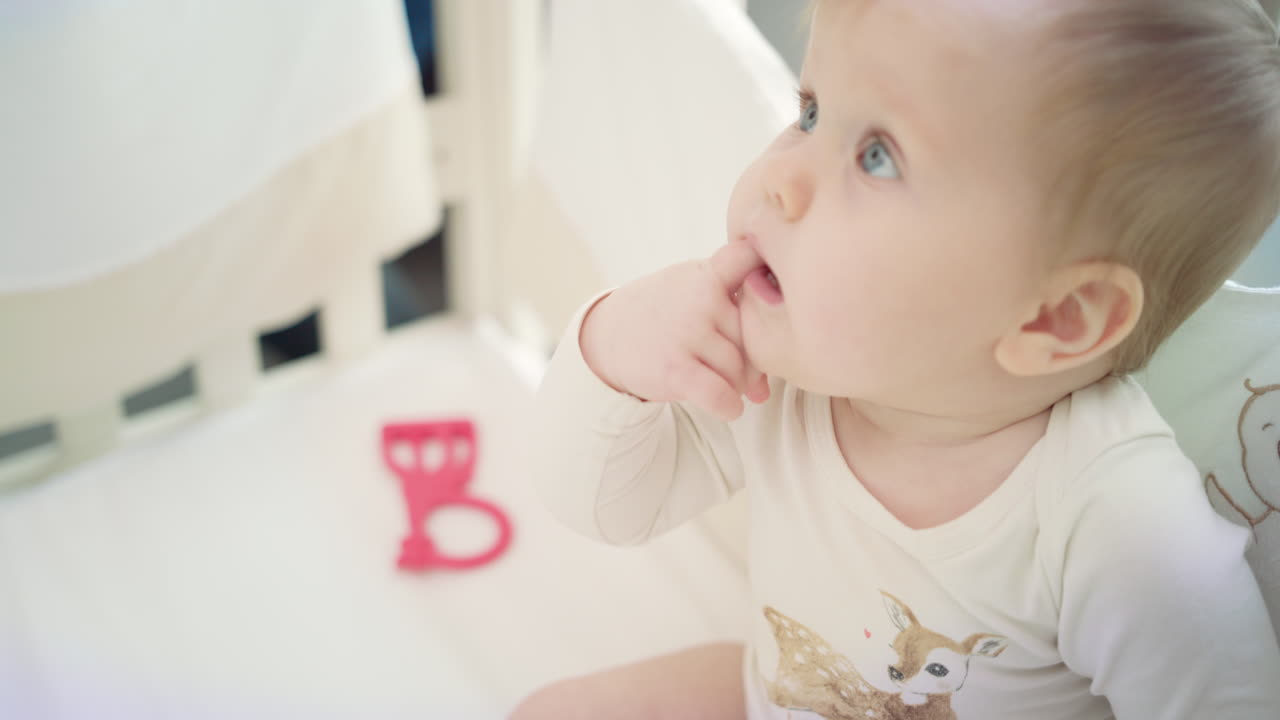 침대에 앉아있는 작은 아기와 성장하는 손가락. 불만족한 작은 아이