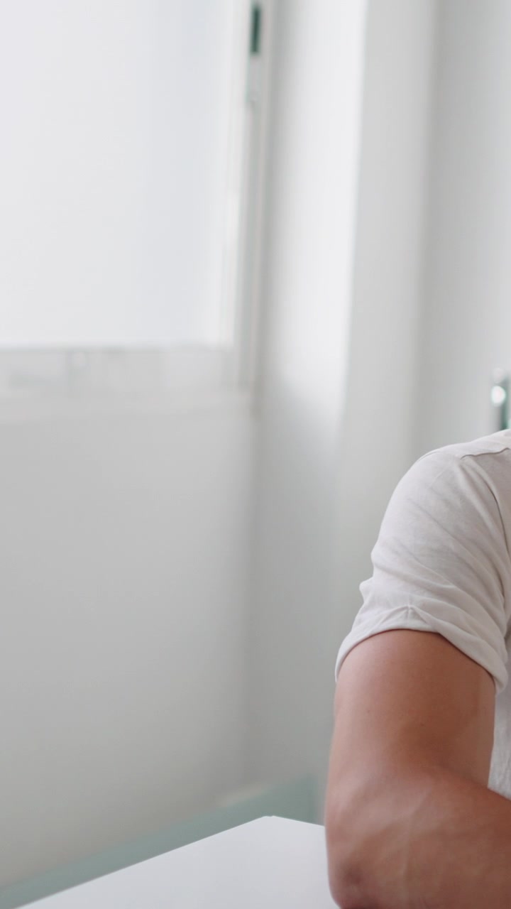 Close-up of a man in a white t-shirt sitting at a desk