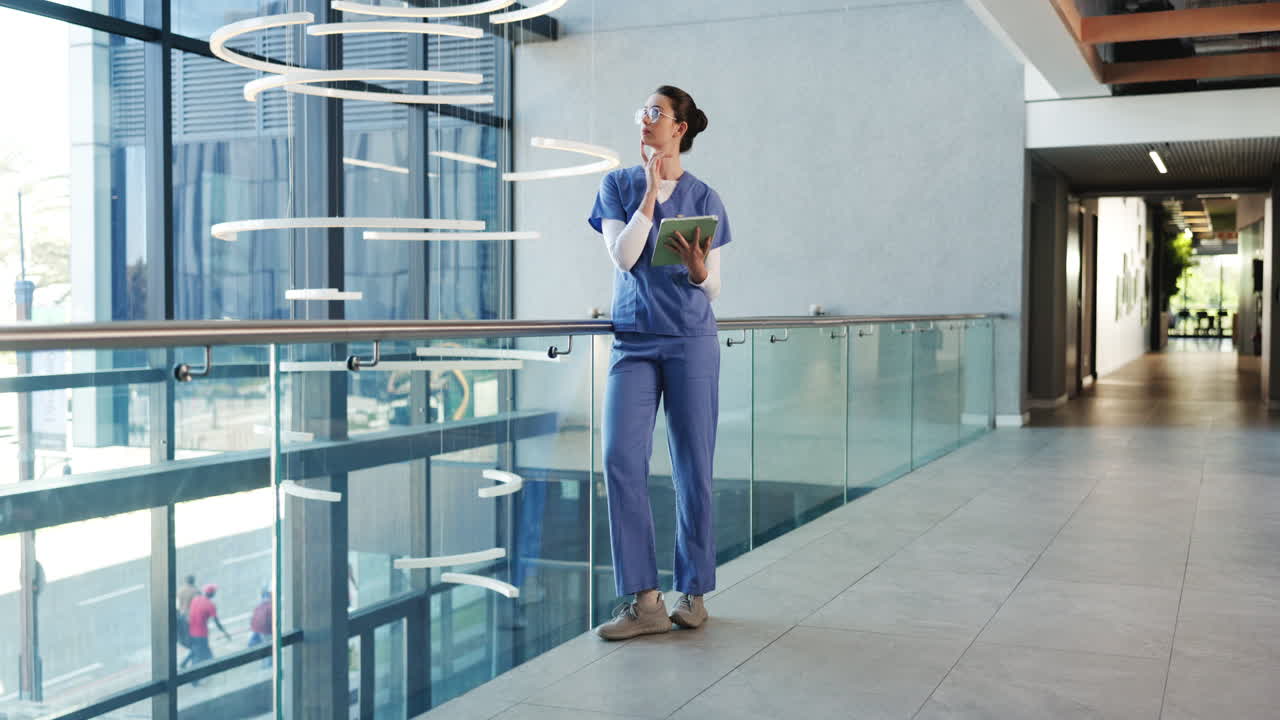 Profissional de saúde feminina em pé usando um tablet em hospital moderno.