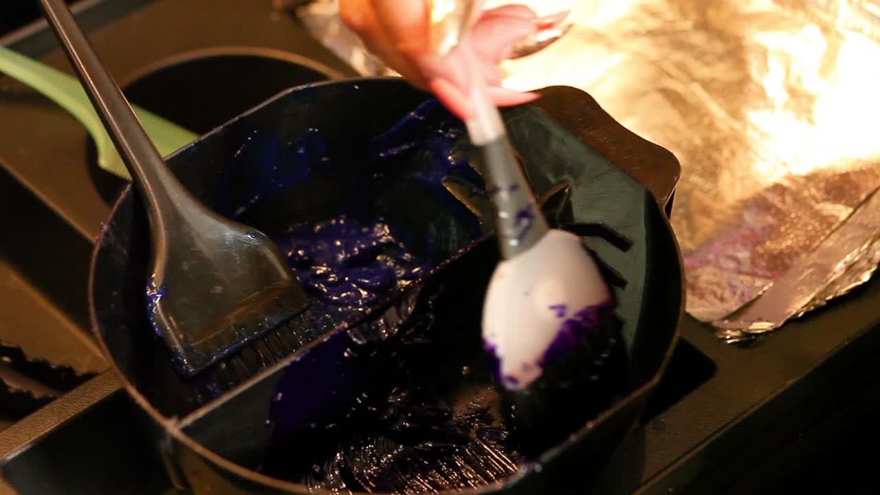 미용사가 보라색 머리 염색약에 브러시를 바르다