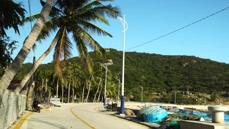 Small-fishing-port-in-Vinh-Hy-Bay,-Vietnam,-empty-walkway-under-palms