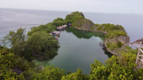 drone flying over karstic cliffs to reveal lagoon in raja ampat indonesia