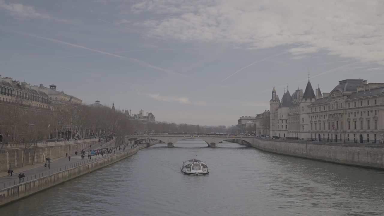 Ampia veduta del fiume Senna, fiancheggiato da edifici storici, con un battello turistico che passa sotto un ponte nel centro di Parigi.