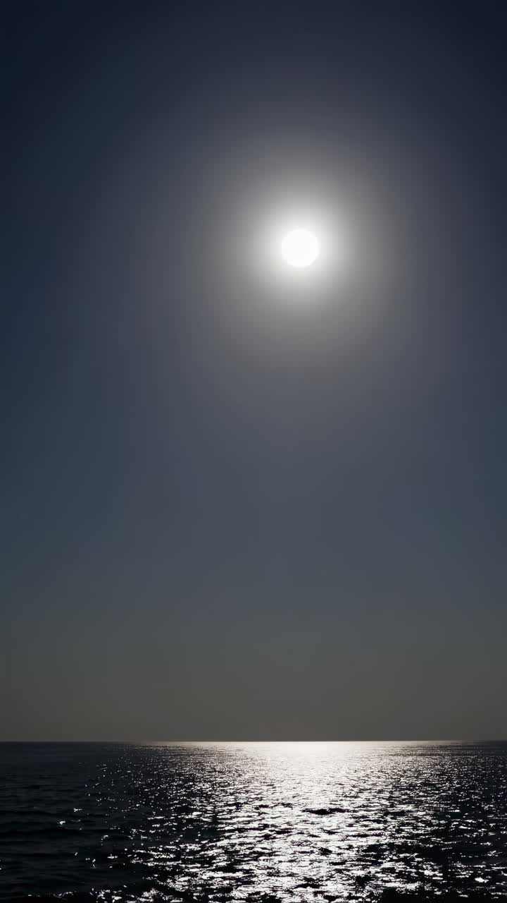 A serene seascape video with a low-angle view capturing the moon's reflection on the water