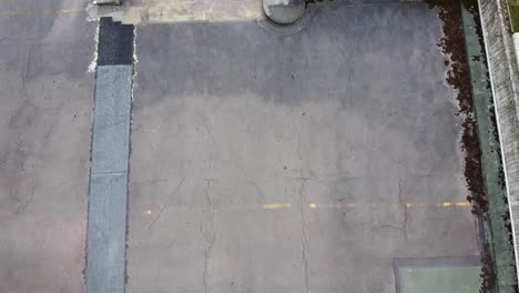 volando sobre el techo del viejo garaje con excavadora y personas con vistas a jardines privados en un día sombreado