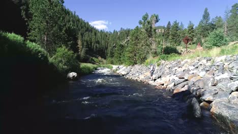 a fly fisherman casts along the banks of a high mountain river