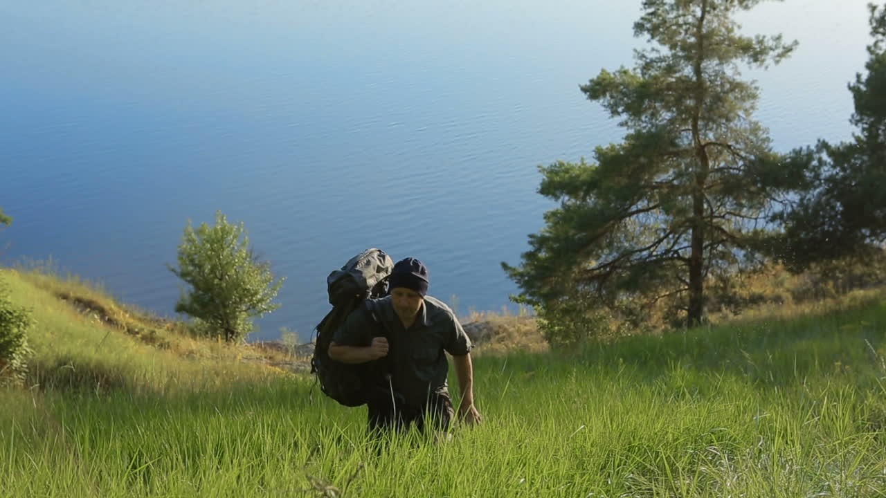 Hiker Walking On A Hill. Active healthy man hiking in beautiful nature