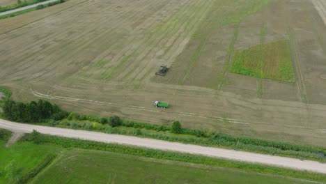 Vista-Aérea-De-Establecimiento-De-Cosechadoras-Cortando-Trigo-Amarillo,-Nubes-De-Polvo-Se-Elevan-Detrás-De-La-Máquina,-Industria-Alimentaria,-Cultivos-De-Granos-De-Cosecha-Amarilla,-Día-Soleado-De-Verano,-Disparo-De-Drones-Avanzando,-Inclinado-Hacia-Abajo