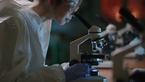 a young female scientist reviews a sample with the professional microscope in the laboratory—a medium tilt-up shot