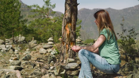 Lady-sits-in-fir-tree-shadow-near-stone-stacks-at-highland