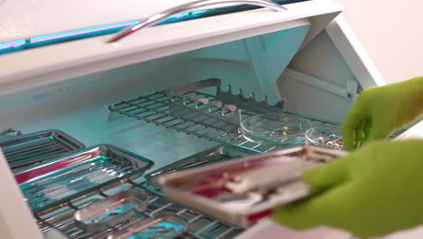 Close-up-shot-of-hands-in-gloves-taking-instruments-from-the-box-for-dental-instruments-disinfection.-Ultraviolet-sterile-chamber.-Shot-in-4k