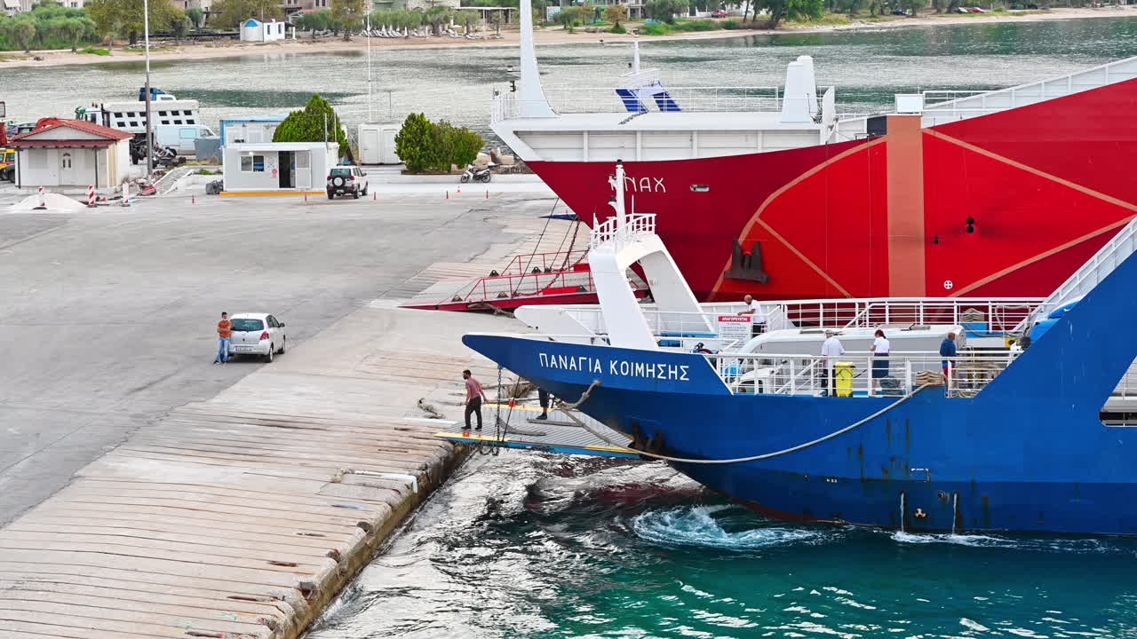 THASOS, GREECE - SEPTEMBER 23, 2020: Moored ferryboats with blue and red exteriors, opened gangplanks in the port, people are walking out of the ship