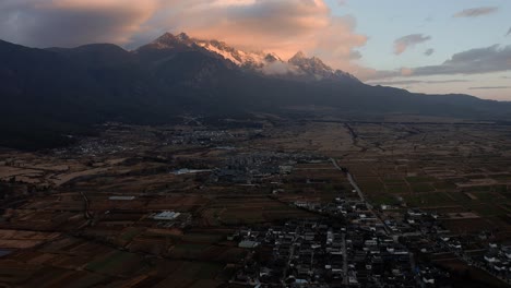 Dramatic-sunrise-over-Jade-Dragon-Snow-Mountain-and-Lijiang-city-China,-aerial