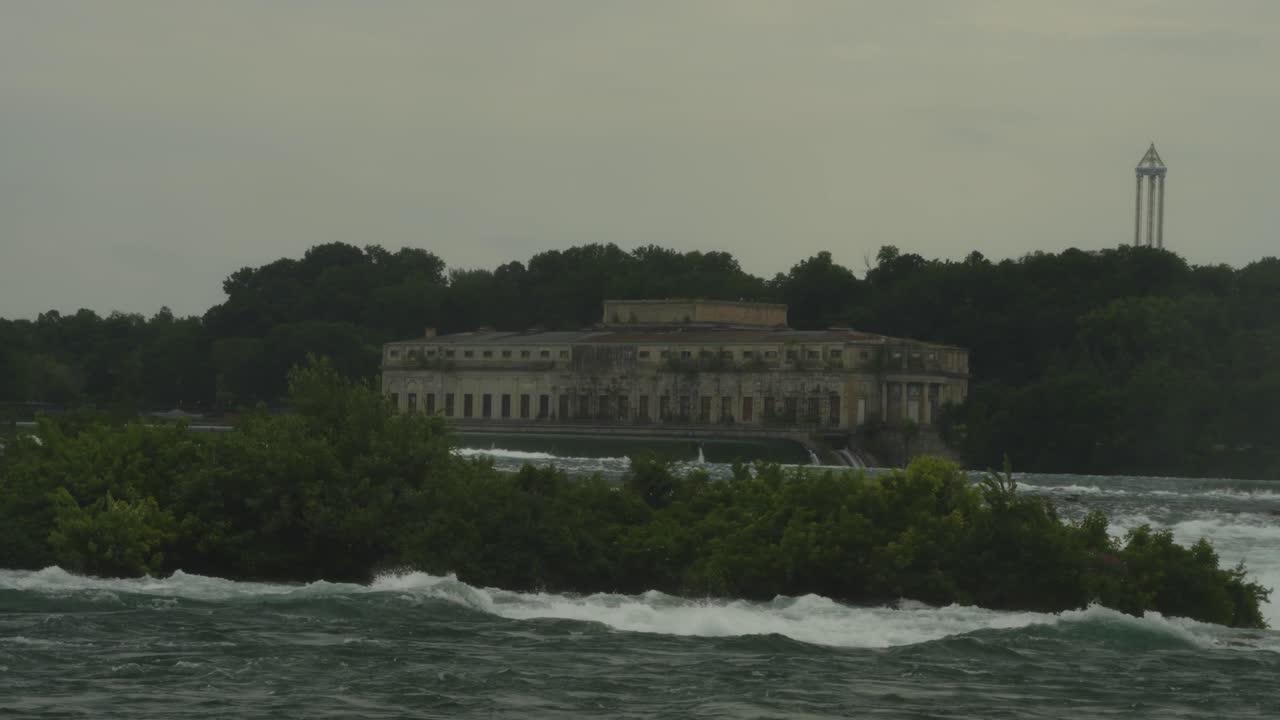 An abandoned power station stands solemnly across the Niagara River, surrounded by swirling currents and overgrown greenery