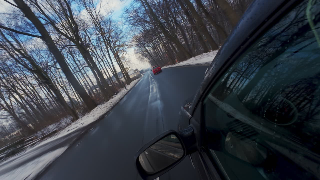 Inquadratura con angolazione olandese da un'auto che viaggia lungo una strada invernale bagnata fiancheggiata da alberi spogli. Ideale per viaggi stagionali, solitudine o temi di viaggio malinconici