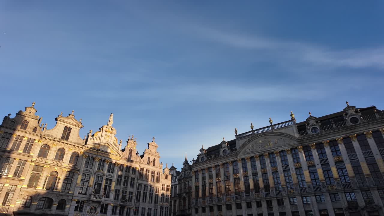 Panorâmica lenta da esquerda para a direita pelas construções da Guildhall na Grand Place, iluminadas pelo pôr do sol de inverno com a decoração de Natal visível