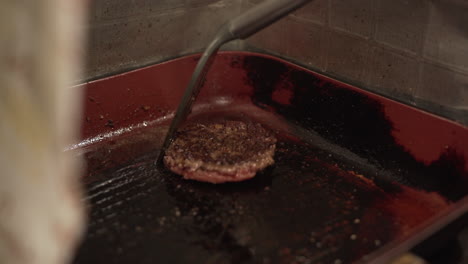 Flipping-Burger-Patty-With-Slotted-Turner-In-Frying-Pan