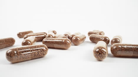 close-up of scattered herbal supplement capsules on a bright white background