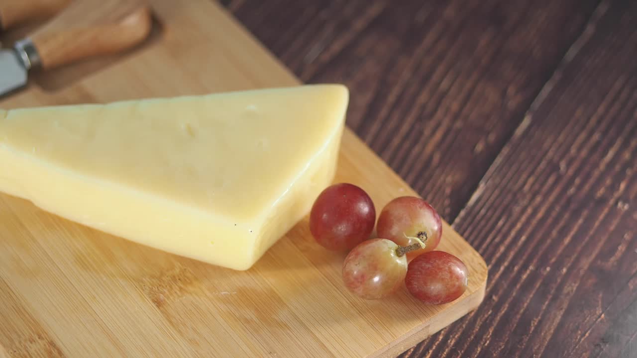 queso y uvas sobre una tabla de cortar de madera