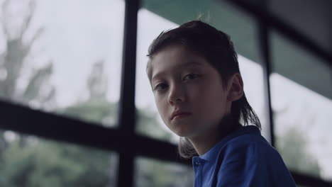 depressed boy watching out window in school close up. pupil feeling loneliness.