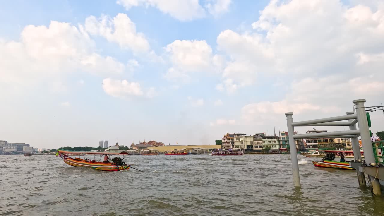 A longtail boat navigates the Chao Phraya River in Bangkok under a bright sky, capturing the bustling river life