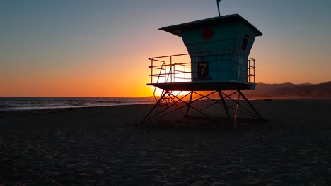 slow crane shot rising up and revealing lifeguard house : tower behind wooden log at sunset at san buenaventura state beach in ventura, california, united states