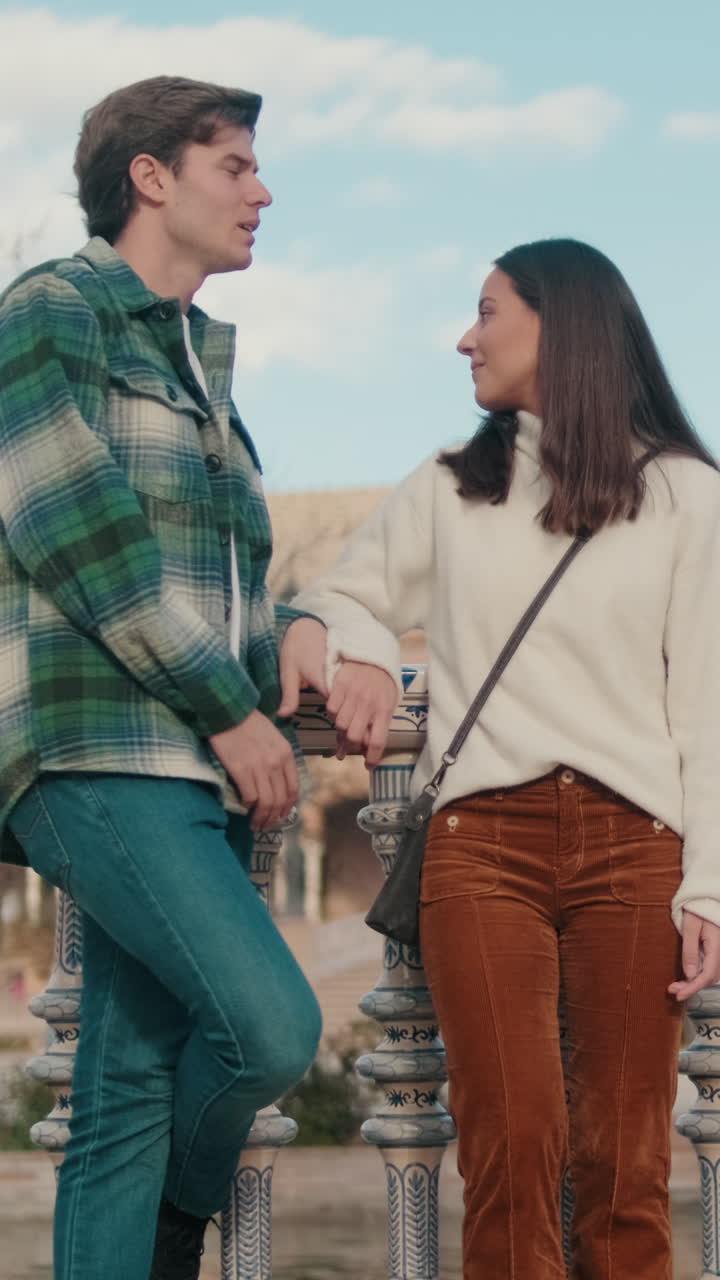 Happy young young pair man and woman holding hands while standing on bridge