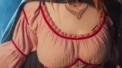 close-up portrait of a woman wearing a pink dress with red trim and a sparkling necklace.