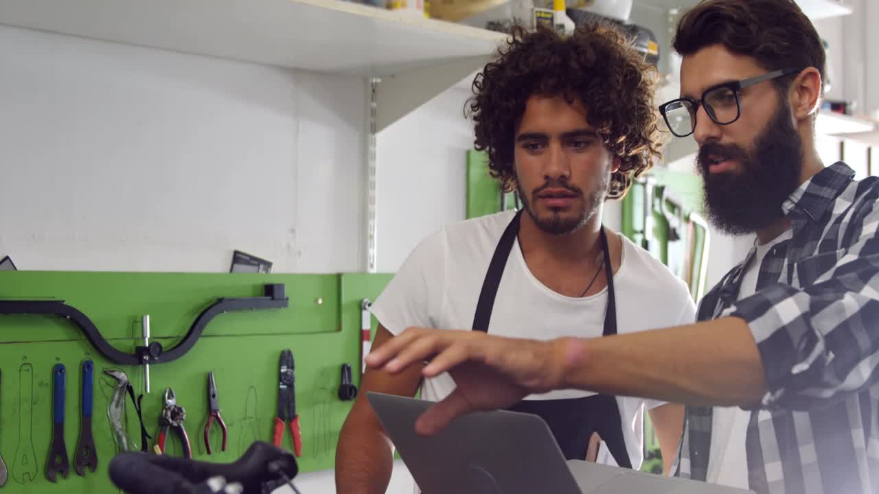 mecánicos discutiendo en la computadora portátil en el taller