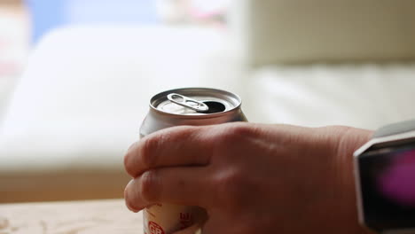 woman opening a can of soda using the ring pull and then drinking