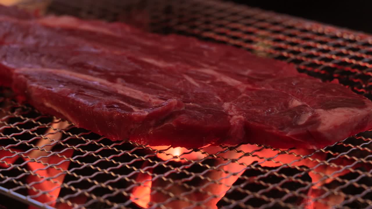 맛있는 스테이크가 나무 석탄 위에 여 있습니다.