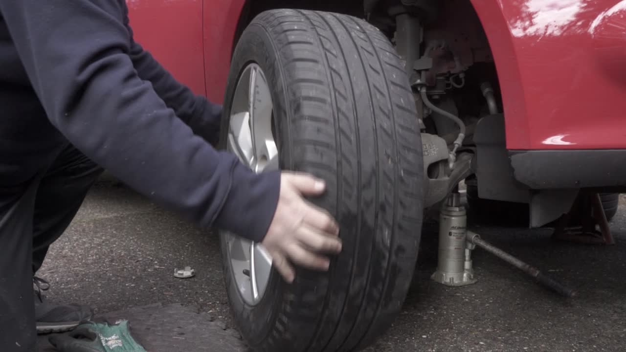 Installing the front tire on a car and hand tightening the lug nuts