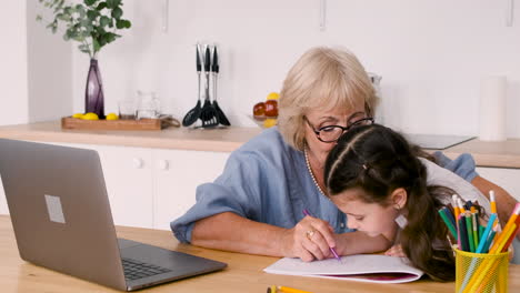 grandmother and granddaughter drawing together sitting at table in kitchen