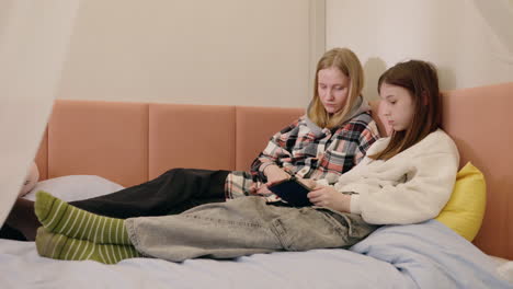 two girls on a bed using a tablet