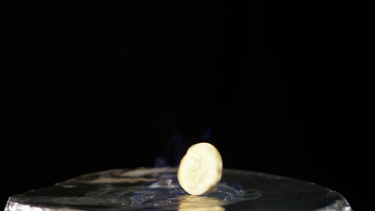 Bitcoin spinning on silver surface in blue flame burning against black background, positioned on bottom of frame.