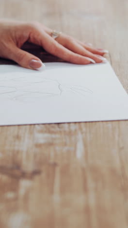 dressmaker is drawing a creative design of a modern clothing indoors. female's hands of a young tailor on the wooden table with a pencil. feminine hobby. vertical video