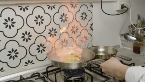 chef adds oil onto hot frying pan with lasagna