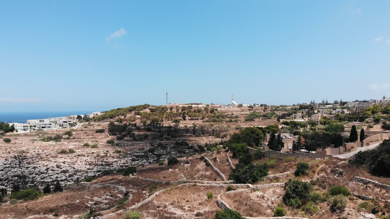vista aérea hacia atrás de los campos secos de la isla mediterránea en un caluroso día de verano desde la cima del mundo, gharghur, malta