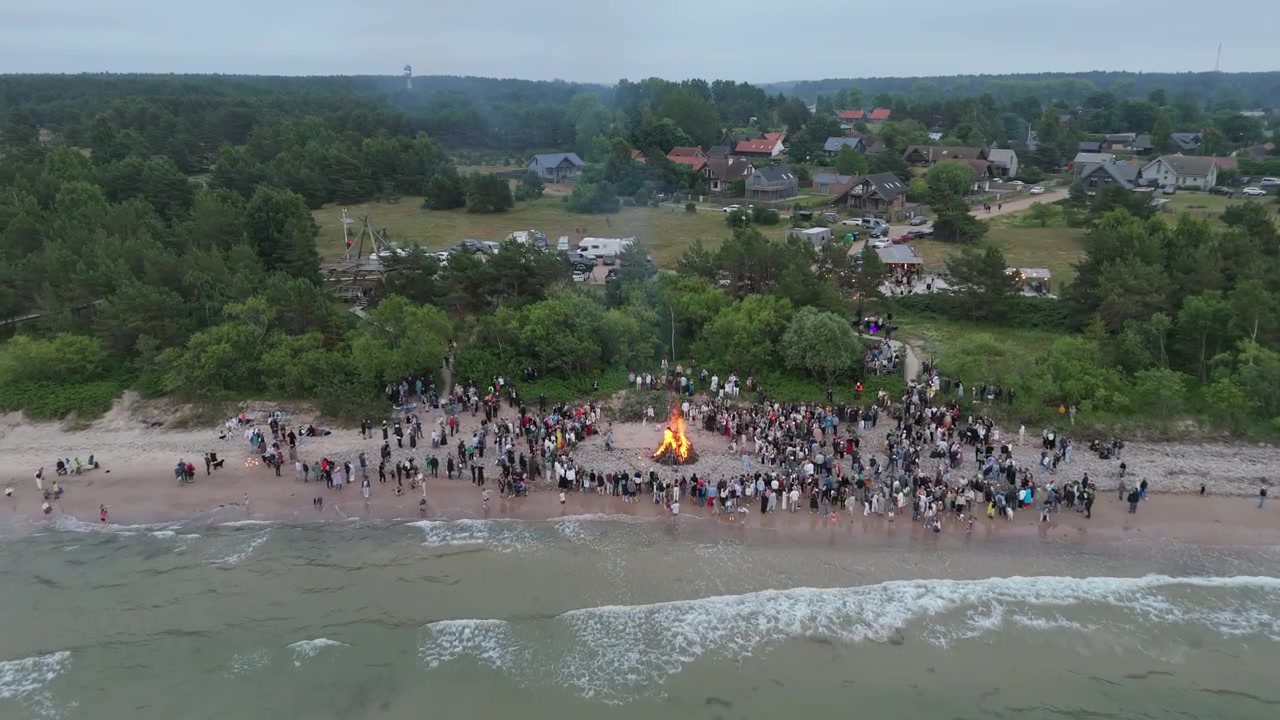 Celebration of the Midsummer Holidays (Ligo) in Pavilosta, Latvia. A Lot of Unrecognized People Standing by a Burning Fire on a Midsummer Night at the beach West Coast of the Baltic Sea. Aerial Shot