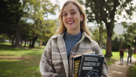 a student holding books in a park