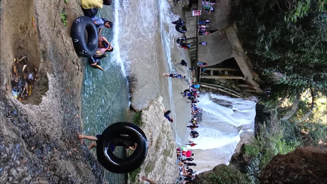 Crowds of people enjoying a waterfall, tubing in the water